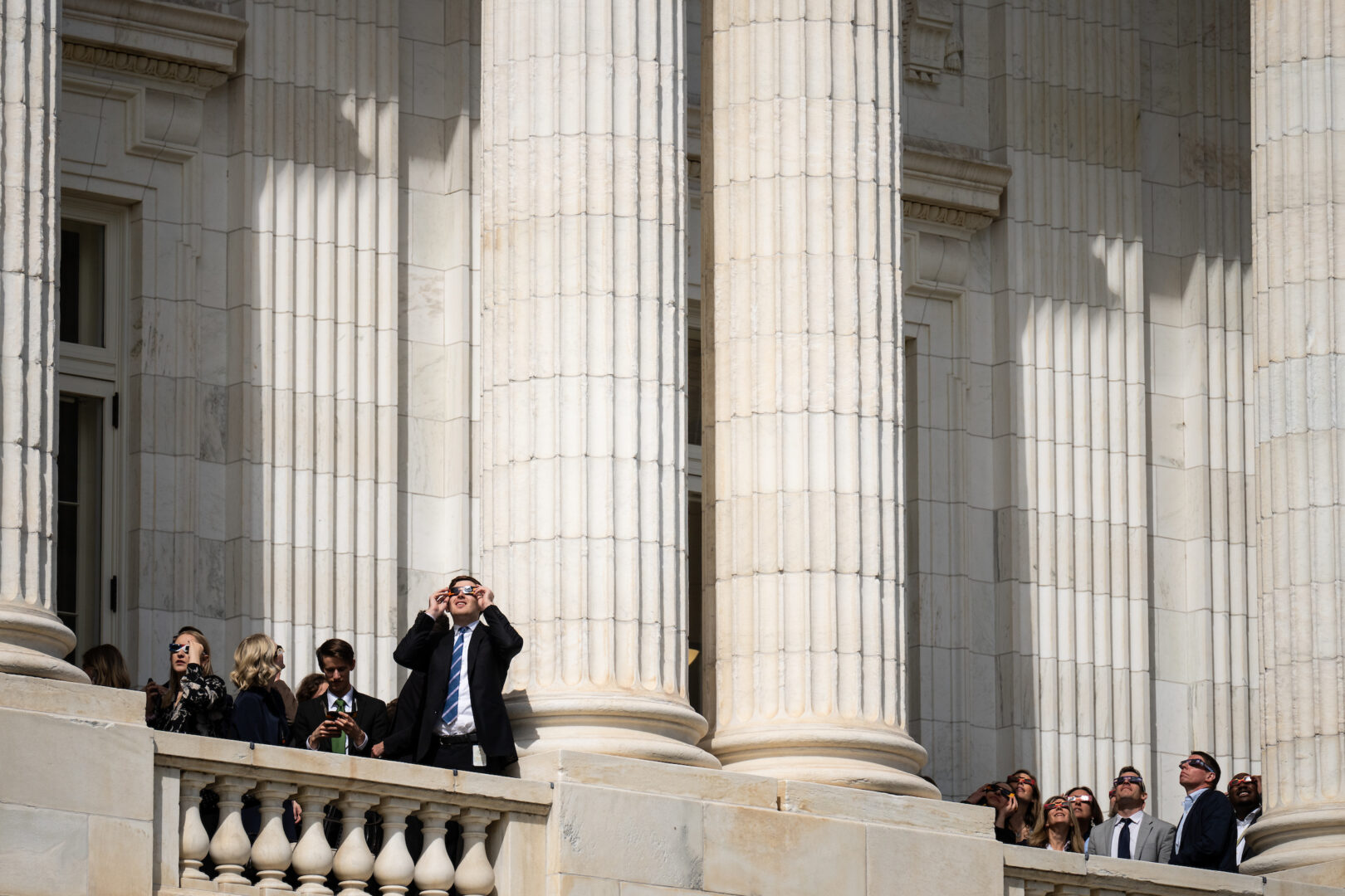 Pay has improved for entry-level congressional staffers in recent years, but 7.6 percent of Senate aides still made below a living wage in 2023, according to a new report from Issue One. Above, staffers stand on balconies of the Russell Senate Office Building to view the solar eclipse on April 8.