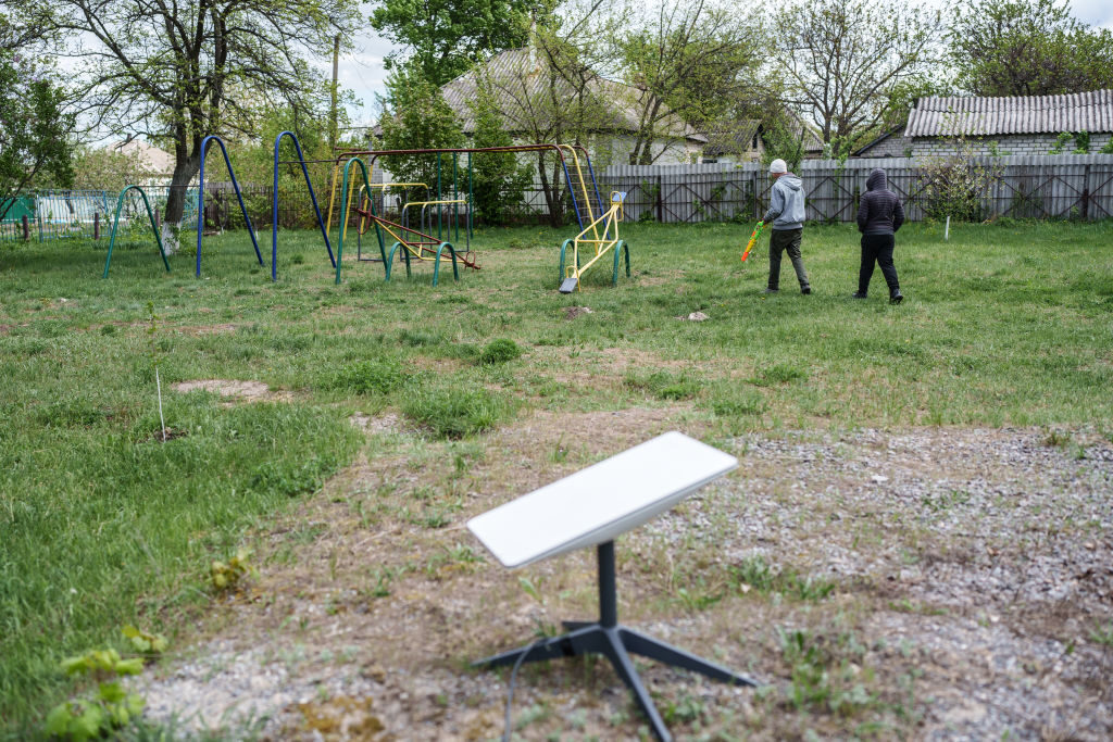 Children walk by a Starlink terminal near the community center in the Ukraine village of Rubtsi on April 19.