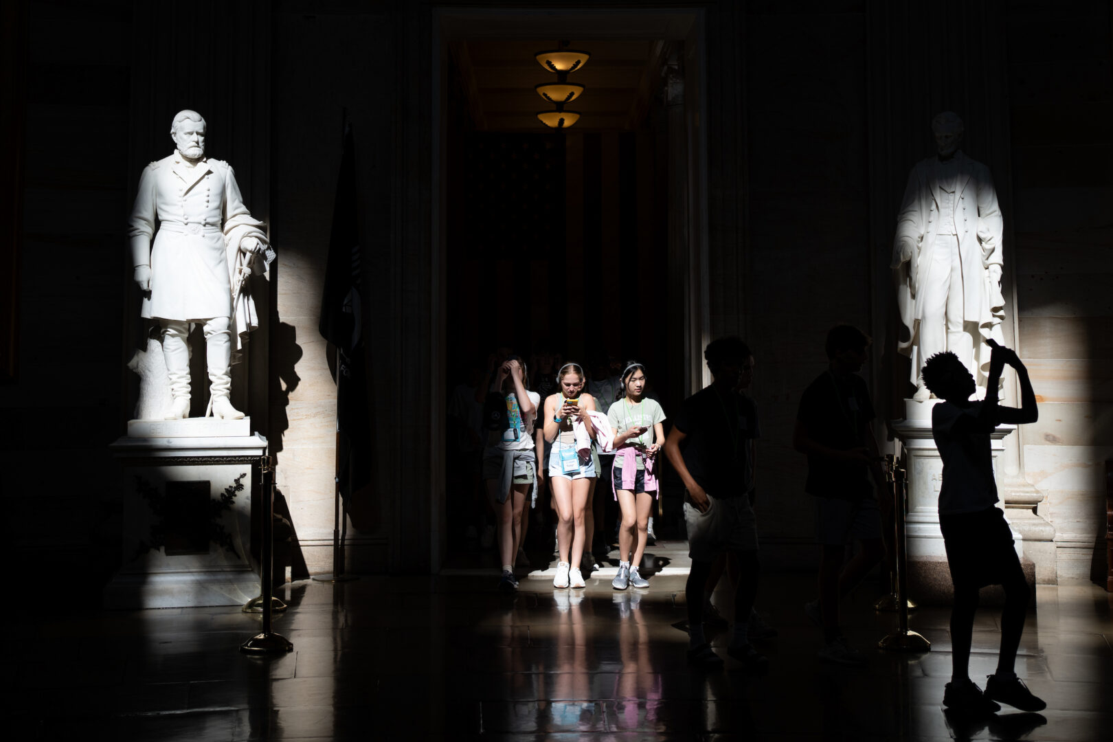 A tour group is seen entering the Capitol Rotunda on Wednesday morning as sunlight illuminates the statues of Ulysses S. Grant, left, and Abraham Lincoln.